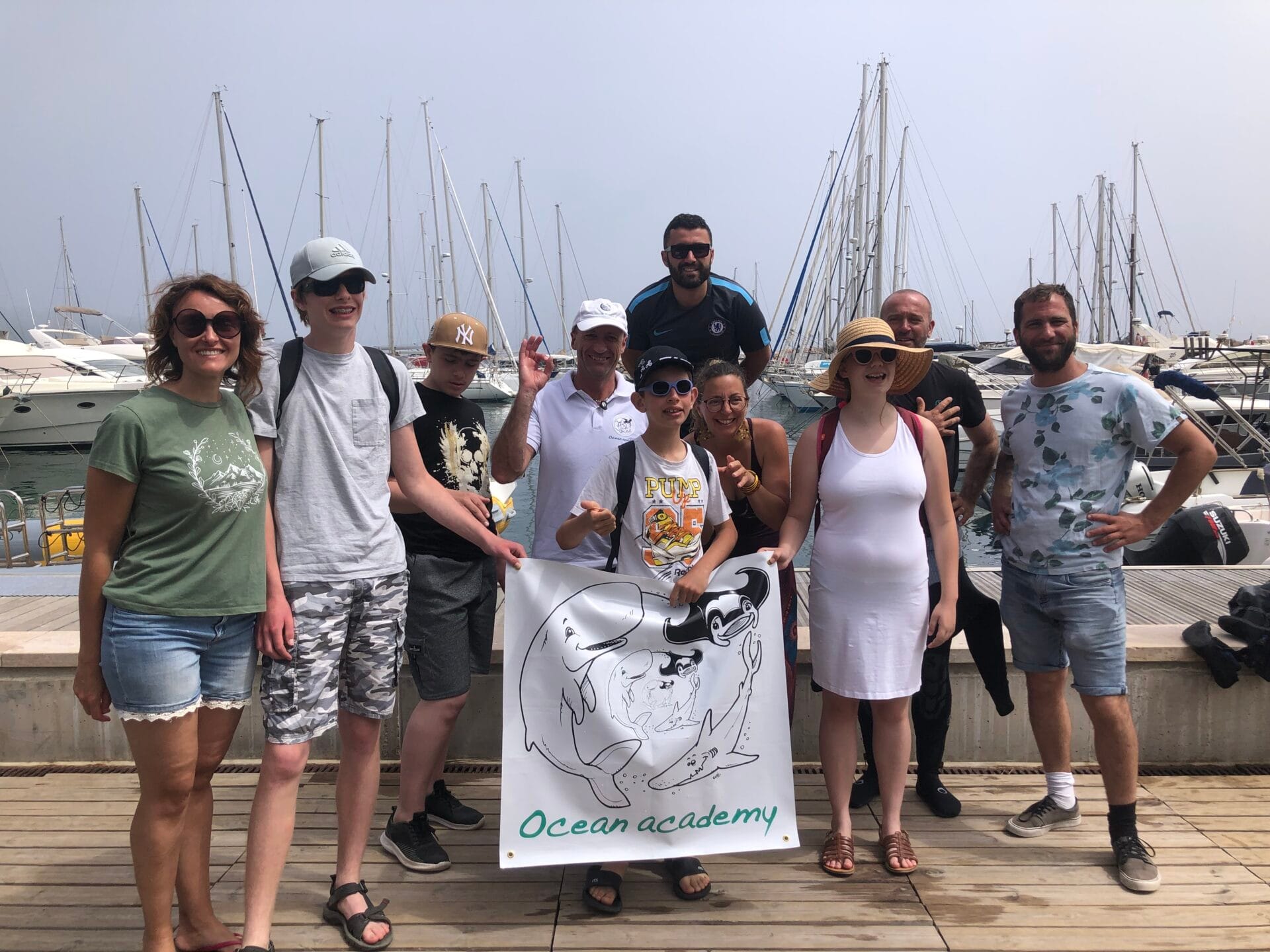 groupe de jeunes dans un port qui portent la banderole ocean academy