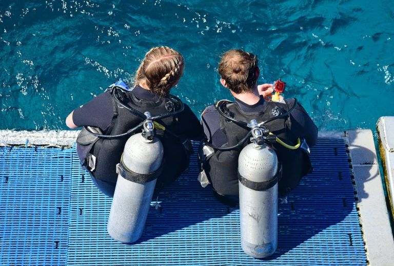 Jeunes plongeurs assis au bord d'une piscine avec leurs équipements.