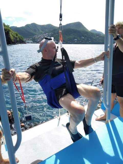 Un homme avec un masque de plongée sur le front accroché dans un harnais sur un bateau.