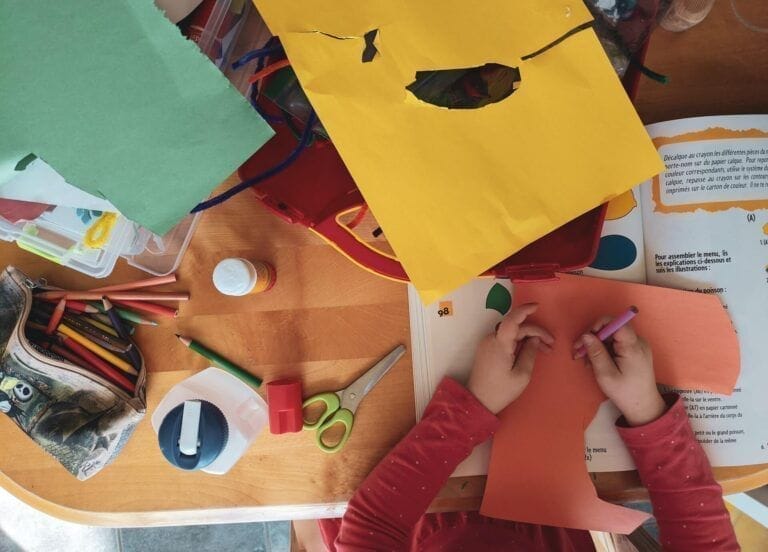 un enfant vu de haut en train de faire des travaux manuels sur une table