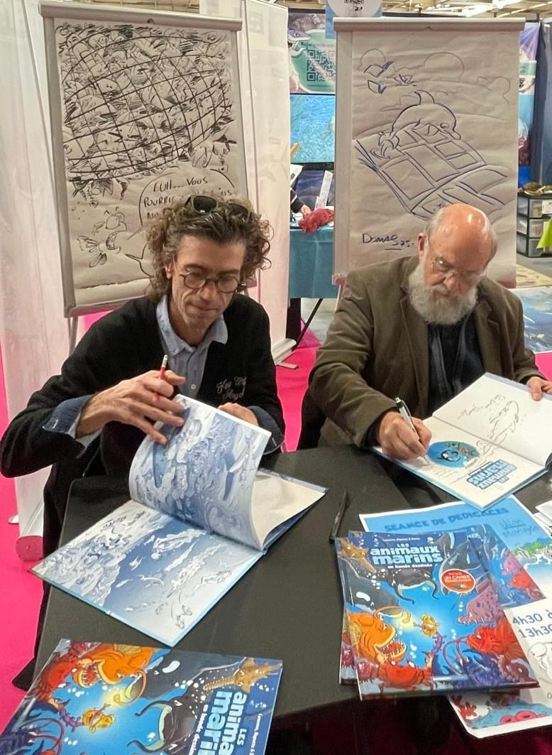 Les deux dessinateurs occupés à faire des dédicaces
